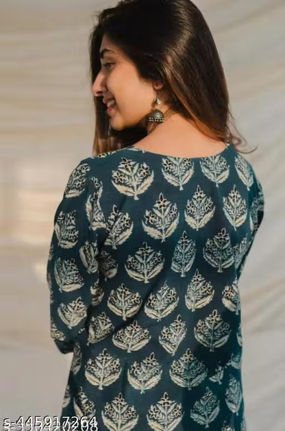 Woman wearing a dark green dress with white floral patterns against a neutral background